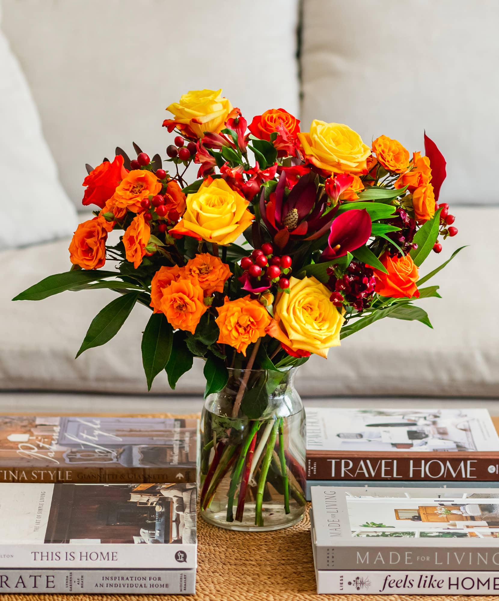 Vibrant floral bouquet featuring roses in warm hues, accented with lush greenery and berries.